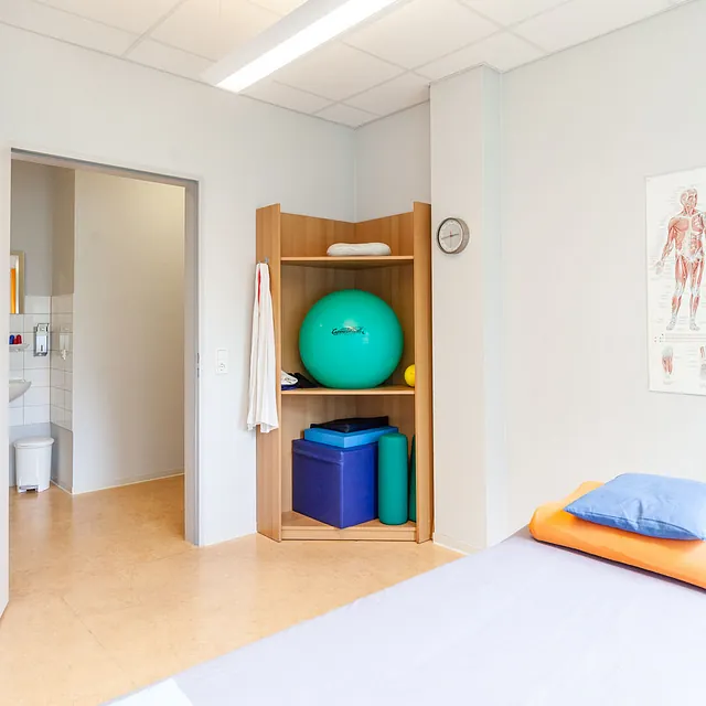 Behandlungsraum mit Liege und Regal mit Geräten