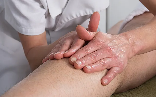 Frau behandelt Bein von Patienten