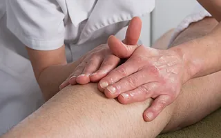 Frau behandelt Bein von Patienten